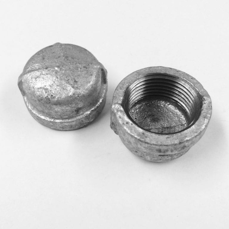 Two galvanised pipe caps lying next to each other, one of the caps kept inverted.